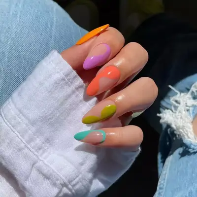 A hand with long almond-shaped nails in a multicolored, gradient style design