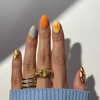 A hand with nail art featuring an intricate design, accessorized with multiple rings