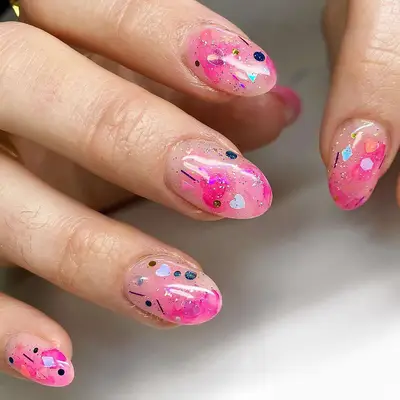 A pink jelly manicure with heart and glitter details