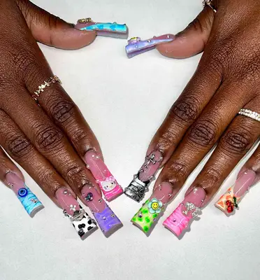 Duck nails with mismatched designs including cow print, evil eyes, Hello Kitty, cherries, and more