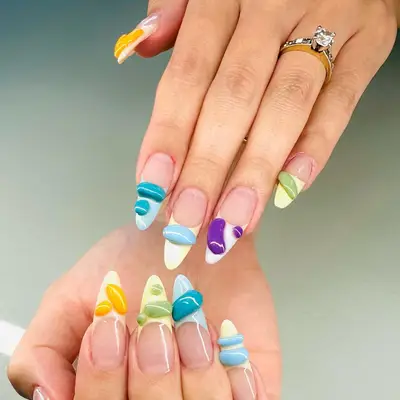 French manicure with different colored tips and 3D blob designs on the tips