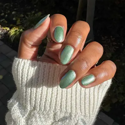 close up of hand showing off fresh manicure, sparkly sage green nails
