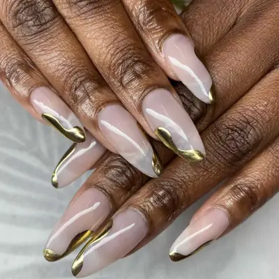 close up of hand showing off fresh manicure, bare base with chrome gold swirly tips
