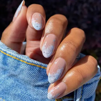 close up of hand showing off fresh manicure, nude base with white and blue tips, silver sparkles