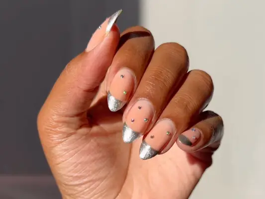 close up of a studded manicure with silver French tips
