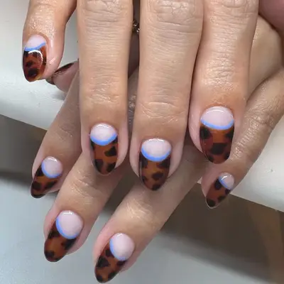 tortoise shell half moon nails with a blue trip and nude polish