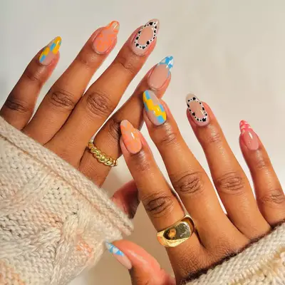 Nude nails with pastel designs and cow print circles