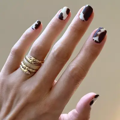 close up of pink crocodile print manicure against white background