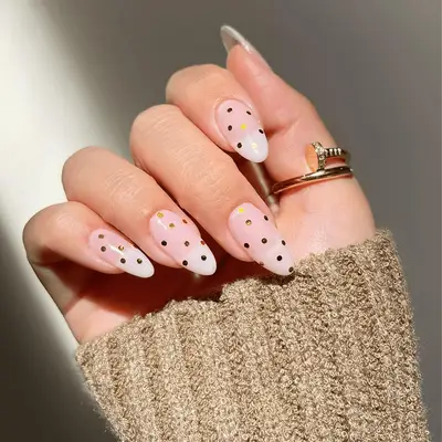 Hand with polka-dotted manicure and rings