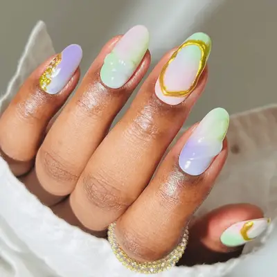 Hand with long fingernails featuring intricate multicolored nail art designs and patterns