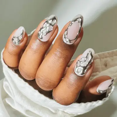 A close-up of neatly manicured nails with decorative metallic patterns