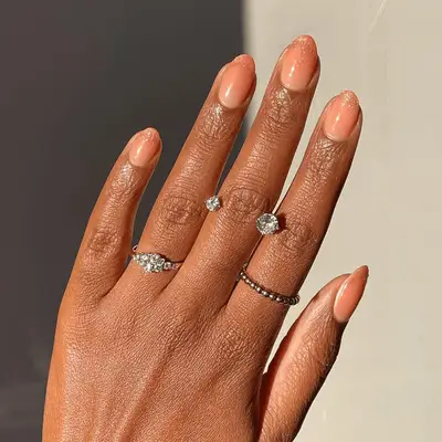 A hand with manicured nails and silver rings on the fingers