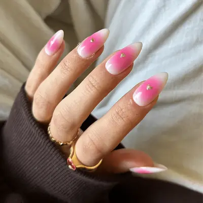 Hand displaying manicured nails with a gradient design and small heart accents