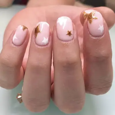 Pink-toned nude nails with gold and white stars
