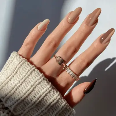 Close up of a manicure with a creamy light brown base and mocha swirls