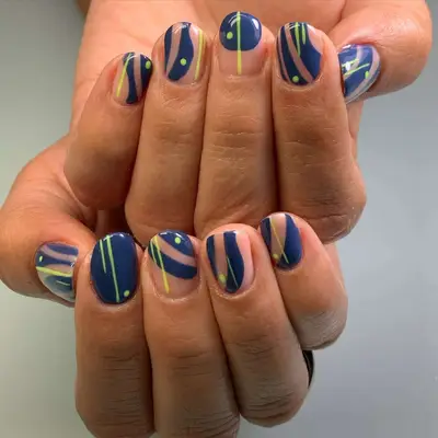Close-up of manicure featuring blue and yellow abstract stripe and dot designs