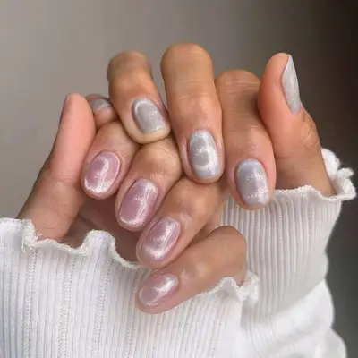 Hands showing manicured pink and white velvet nails with a pearlescent finish