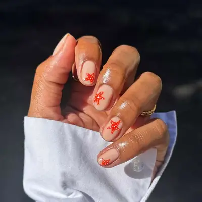 Close-up of a manicure featuring small red starfish designs