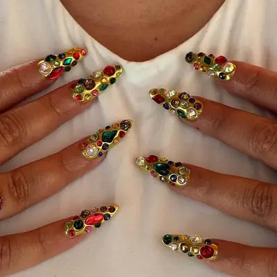 a molten gold chrome manicure bedecked with jewels