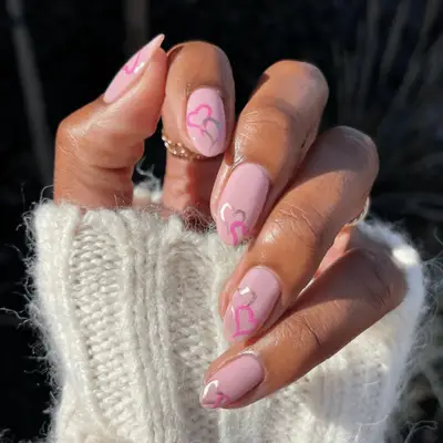 A manicure with light pink manicure with pink and silver heart nail art