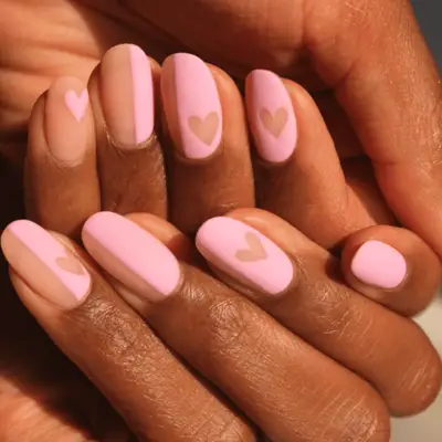 Manicure with half pink half nude polish adorned with hearts 