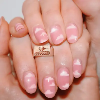 Manicure with light pink bade and a cloud design on top