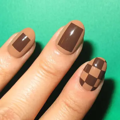 A brown manicure with checkerboard and square accents
