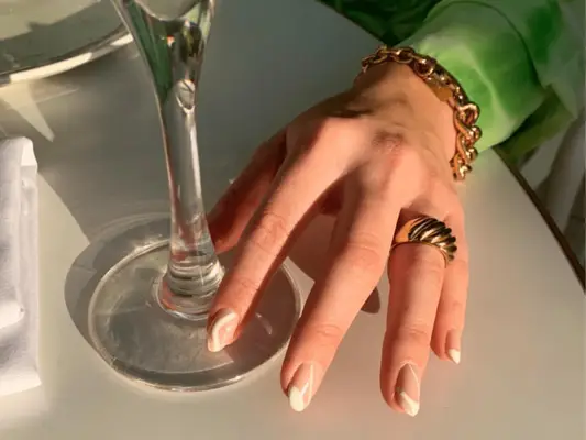 Close up of a hand wearing gold jewelry and long nails 