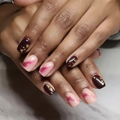 A burgundy manicure with gold foil flake details