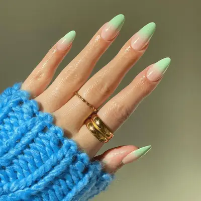 A close up of light green ombrÃ© nails