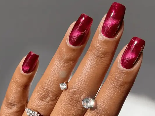 close up of red velvet manicure on white background