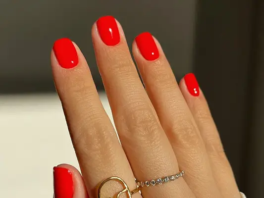 A short, square tomato-red manicure