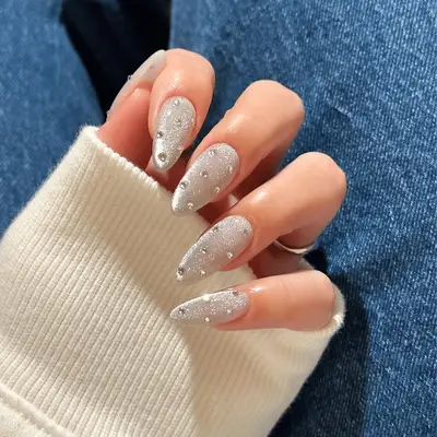 Hands with manicured nails featuring decorative gemstones and patterns