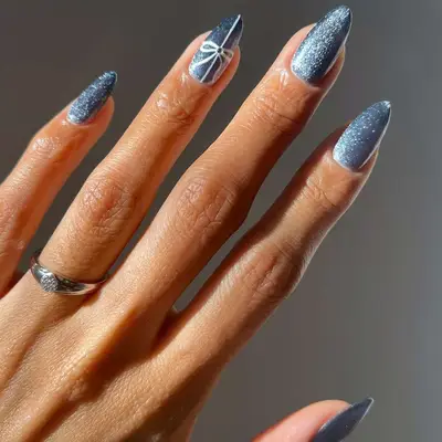 A blue velvet manicure with a white bow accent