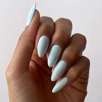 A iridescent blue chrome manicure with a white snowflake detail