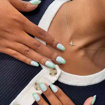 A minty green manicure with square designs on almond tips