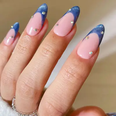 A blue velvet French manicure with gemstone accents