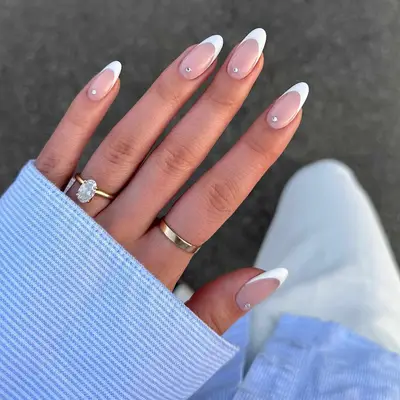 A French manicure with white tips and gemstones at the cuticle