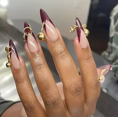 A sharp burgundy French mani with gold piercings