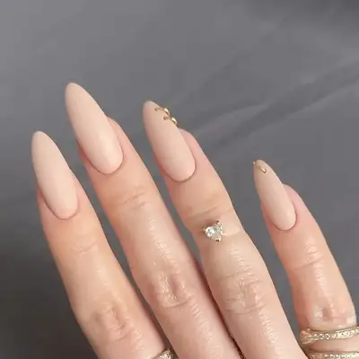 A long, nude almond-shaped manicure with gold hoop piercings