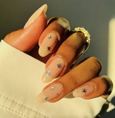 Nude almond-shaped nails with holographic starburst nail stickers