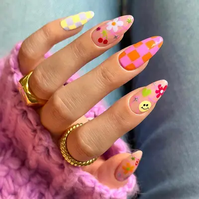 Manicure with colorful checkerboard nails and smiley, flower, heart, sparkle, and cherry emoji designs