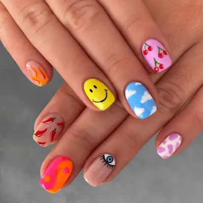 Colorful manicure with smiley face, flame, cloud, cherry, chili pepper, yin/yang, eye, and animal print designs