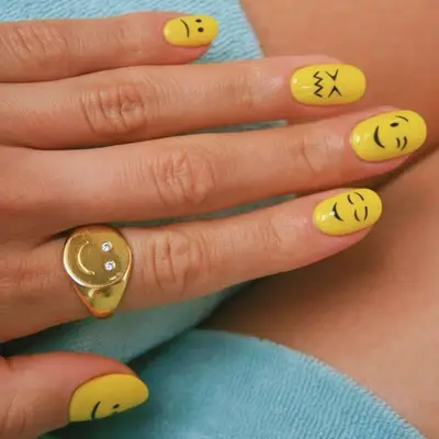 Emoji nails with yellow base and different face designs