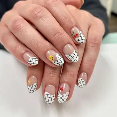 Manicure with grid French tips and smiley face, cherry, lightning, and mushroom emoji designs