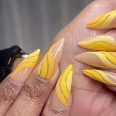 Nude base manicure with swirls in shades of yellow.