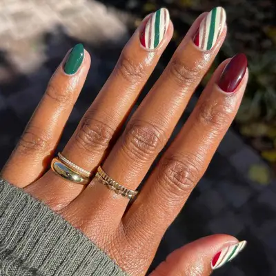 A manicure with accent nails in white, red, green, and gold
