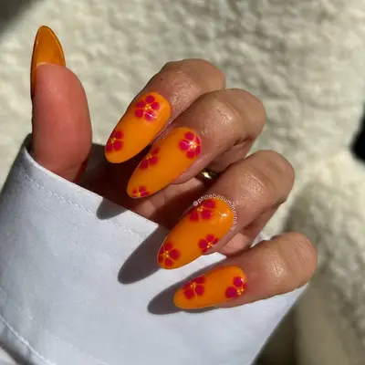 Long orange nails with hibiscus flower detail