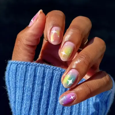 airbrushed rainbow design on nude nails with white star accents