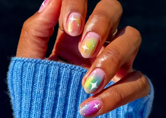 airbrushed rainbow design on nude nails with white star accents